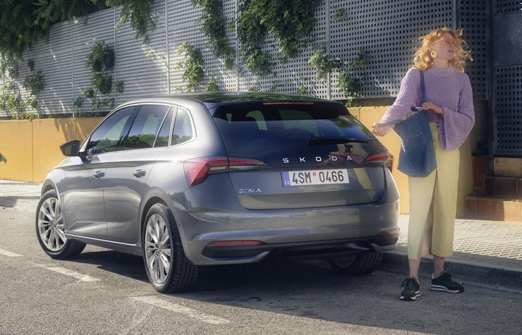 Chica pasando por atrás de un skoda aparcado
