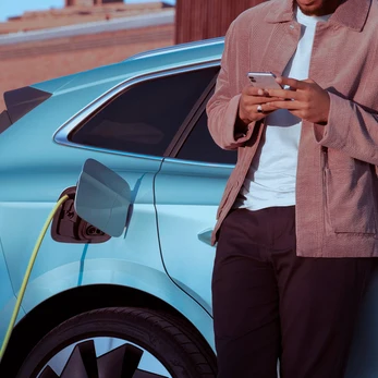 Chico mirando el mobil mientras carga su Skoda