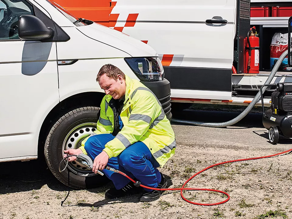 Un hombre del Servicio Oficial de VW revisando la rueda de un vehículo VW.