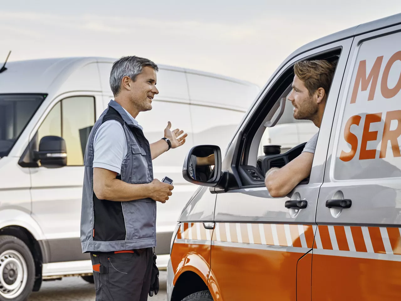 Un hombre de pie hablando con un hombre dentro de un vehículo.