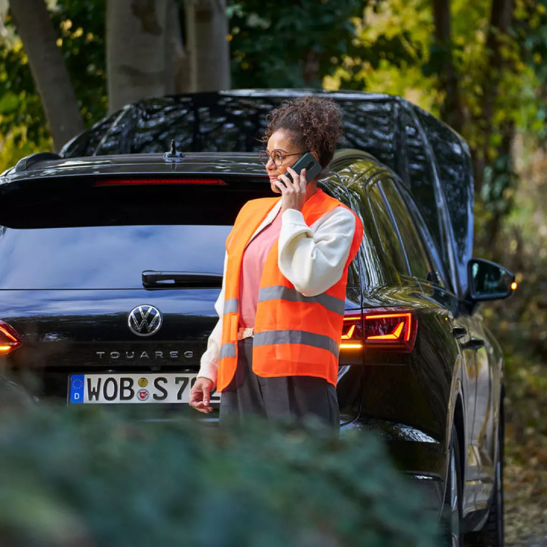 Una mujer al lado de un Volkswagen llamando al servicio técnico